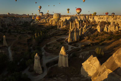 Hot air balloons flying over rocky landscape during sunny day