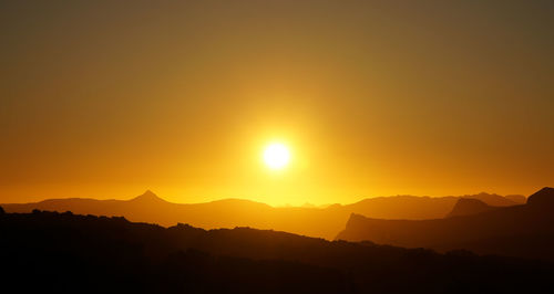 Scenic view of silhouette mountains against orange sky