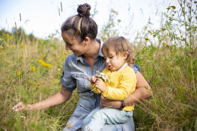 Smiling mother with daughter sitting at field