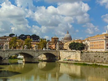 Arch bridge over river against buildings in city