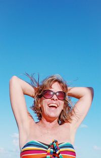 Smiling woman standing against clear blue sky