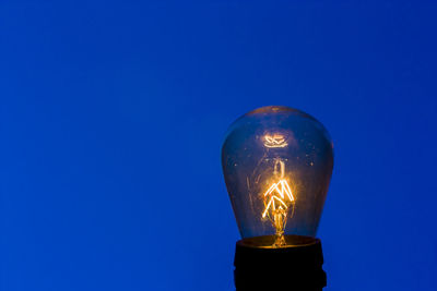 Low angle view of illuminated light against clear blue sky