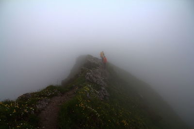 Hikers hiking on mountain during foggy weather