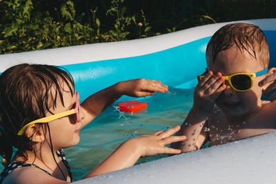 Happy and funny children playing in the pool. friends spend summer leisure together on a hot day