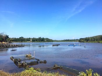 Sailboats moored on river against clear blue sky