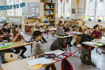 Male and female students attending lecture in classroom at school