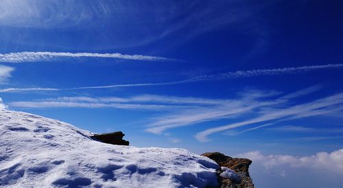 Low angle view of snow covered mountain against blue sky