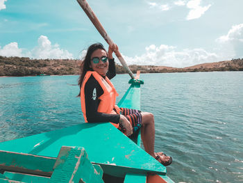 Woman sitting on boat against sky