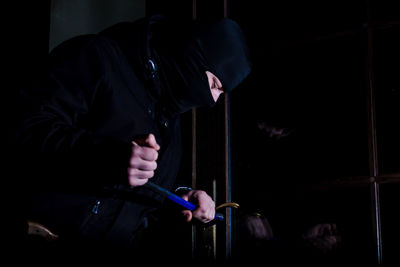 Man holding smart phone while standing in the dark