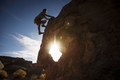 Low angle view of man jumping on rock