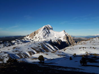 Scenic view of snowcapped mountains against blue sky