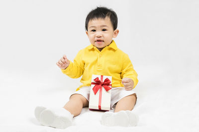 Portrait of young woman sitting against white background