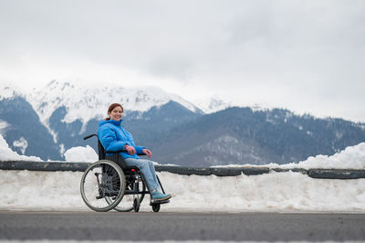 Woman sitting in wheelchair on snow covered mountain