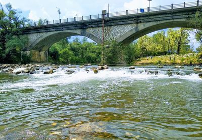 Arch bridge over river against sky