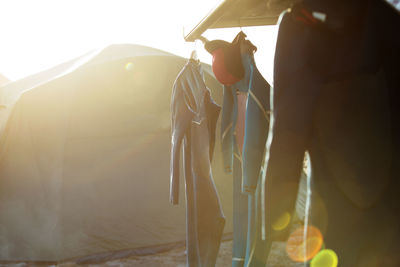 Wetsuits hanging against tent at beach on sunny day