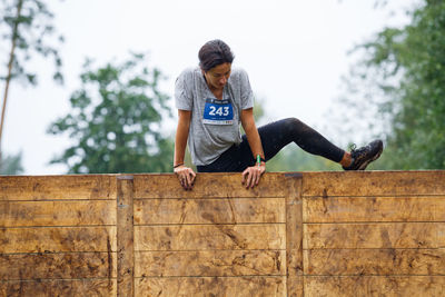 Full length of teenage girl sitting on wooden railing