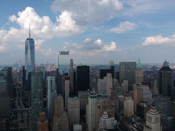 Aerial view of buildings in city against cloudy sky