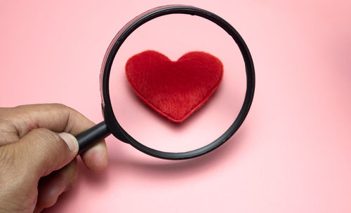 Close-up of hand holding heart shape over white background