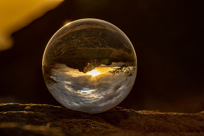 Close-up of crystal ball on rock against sky