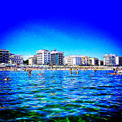 Buildings by swimming pool against blue sky