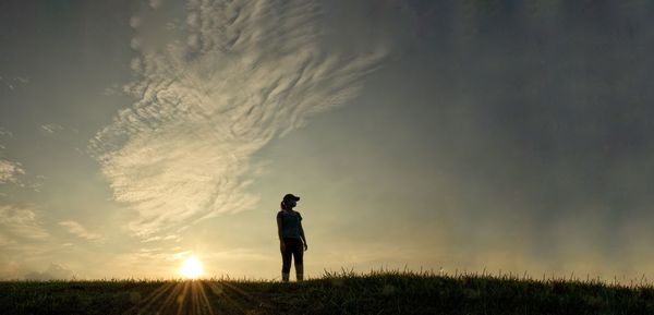 Man standing on field against sky during sunset