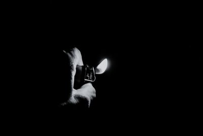 Close-up of hand holding lit candle in darkroom