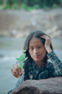 Young woman holding plant outdoors