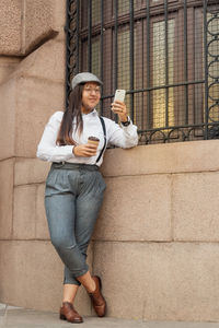 Full length portrait of a woman drinking coffee