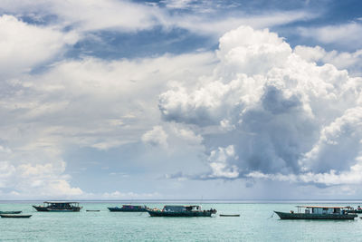 Boats in sea against cloudy sky
