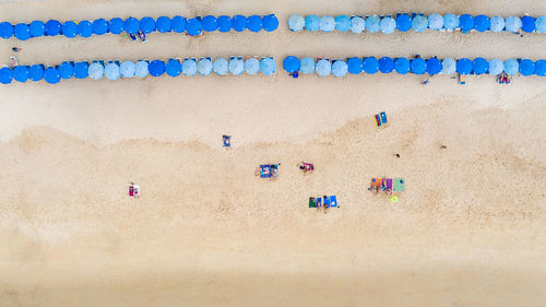 Aerial top view travelling tourists sleeping and relax on the sand beach and umbrella blue thailand 