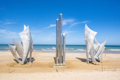 Deck chairs on beach against blue sky