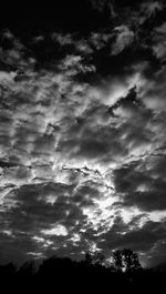 Low angle view of silhouette trees against cloudy sky