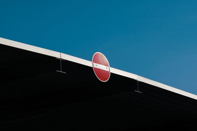 Do not enter metal traffic sign on roof in front of blue sky