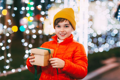 Portrait of a happy boy standing on the evening street and opening a christmas gift. christmas gifts