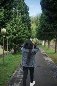 Rear view of woman walking on footpath amidst trees