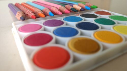 Close-up of multi colored pencils and paints on table