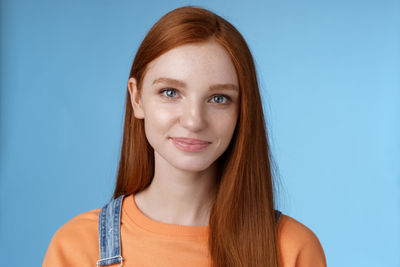 Beautiful redhead woman against blue background