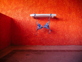 Bikini top hanging against orange wall
