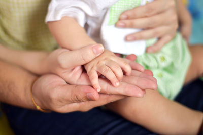 Midsection of couple and baby holding hands