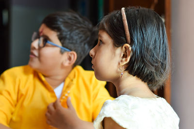 Close-up of siblings looking away while sitting at home