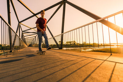 Rear view of man walking on bridge against sky