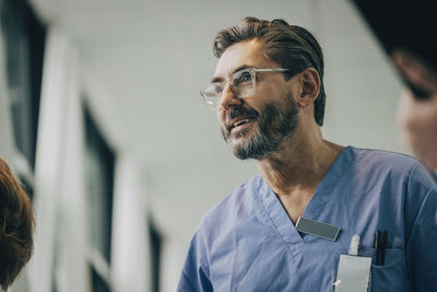 Low angle view of smiling mature male doctor wearing eyeglasses at hospital