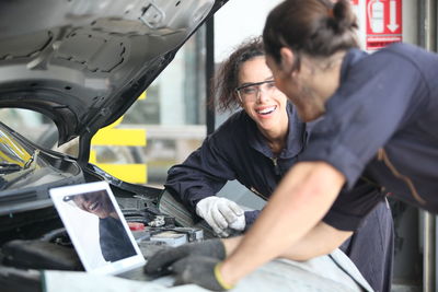 Smiling mechanics repairing car at garage