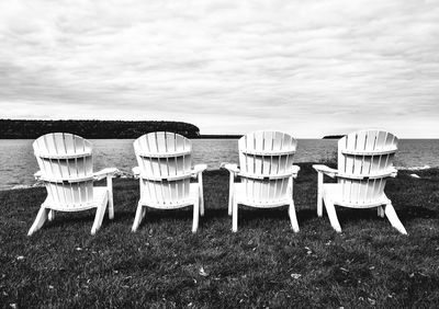 Chairs on grassy field against sky