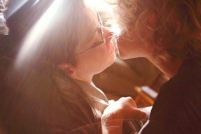 Close-up of mother and son kissing at home on sunny day