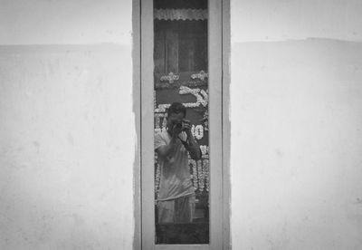 Reflection of man photographing on window