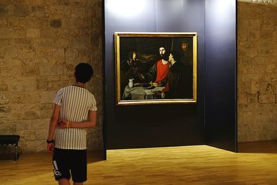 Rear view of man and woman standing against illuminated wall