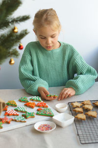 A cute girl prepares bright festive cookies for christmas and new year.