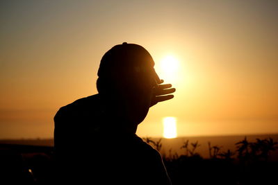 Rear view of silhouette man against orange sky