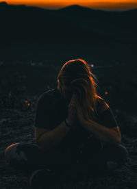 Rear view of woman sitting at sea at night